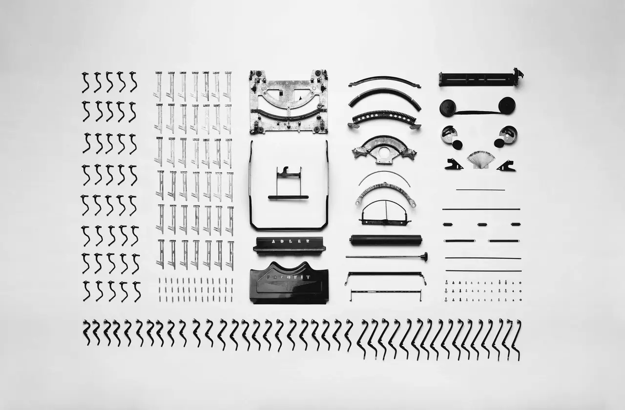 Every part of a typewriter, taken apart and laid out in neat rows on a sheet of paper